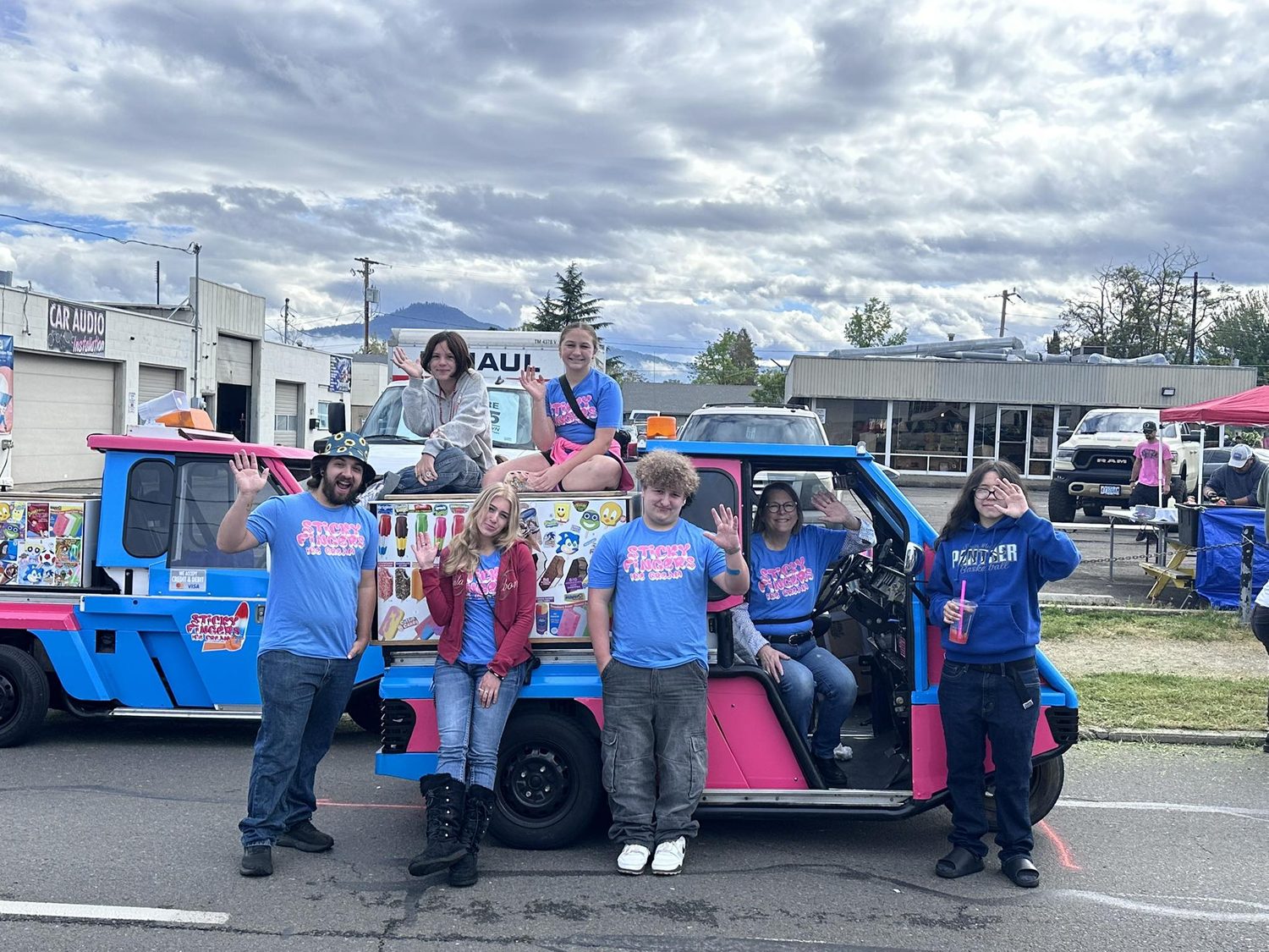 The Sticky Fingers crew waving by a truck at the Pear Blossom Parade in Medford